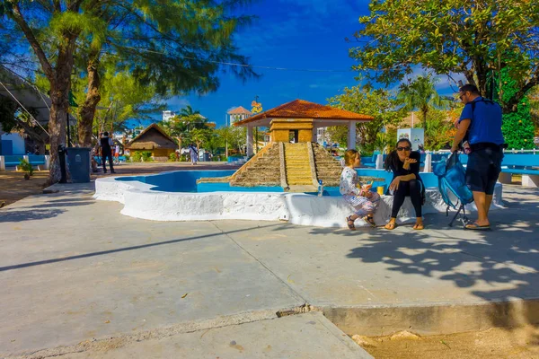 Puerto Morelos, Mexico - January 10, 2018: Unidentified people sitting in the border of a stoned empty fountain of pyramid of yucatan in the middle of the park in Puerto Morelos, Yucatan Peninsula — Stock Photo, Image