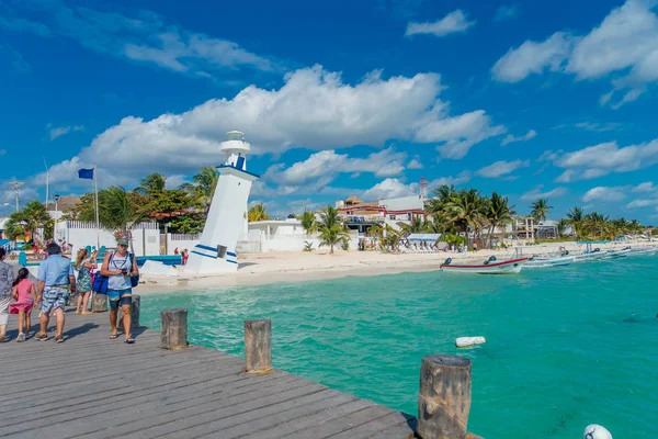 Puerto Morelos, Mexico - 10 januari 2018: Oidentifierade människor gå på utomhus över en träbrygga i Puerto Morelos med en gammal böjd fyr bakom i Mayan Riviera Maya i Mexiko — Stockfoto