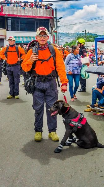 厄瓜多尔基多-2018年1月31日: 在厄瓜多尔基多举行的游行中, 有一只美丽的黑色拉布拉多犬的身份不明男子的户外景观, 救援小组在街上散步 — 图库照片