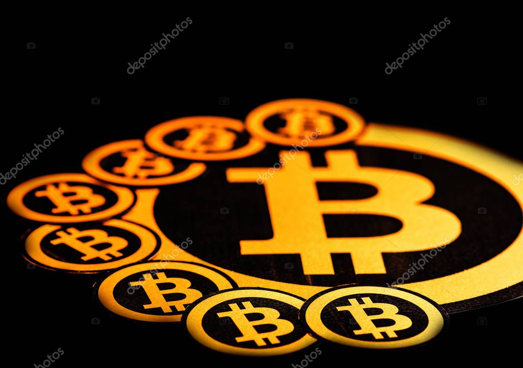 Quito, Ecuador - January 31, 2018: Close up of Golden Bitcoin logo. with small bitcoins logos around the big one. Bitcoin cryptocurrency. Business concept in a black background.