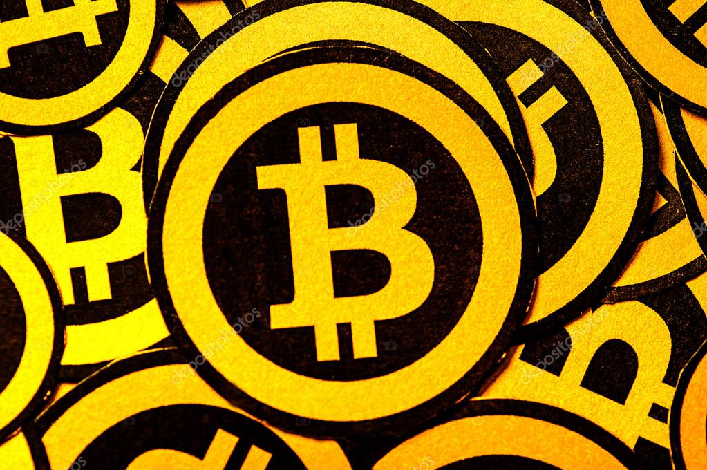 Quito, Ecuador - January 31, 2018: Indoor view of selective focus of Golden Bitcoin logo. with small bitcoins logos around the big one. Bitcoin cryptocurrency. Business concept in a black background.