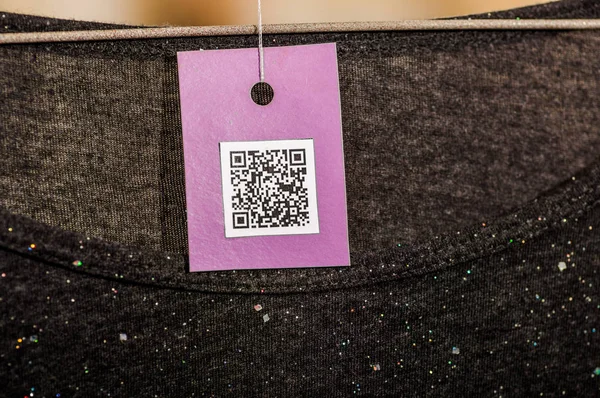 Nahaufnahme einer QR-Code-Information in einem Kleiderschein vor verschwommenem Hintergrund — Stockfoto