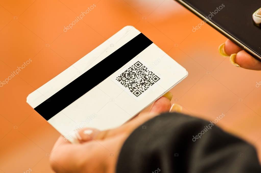 Close up of a woman s hand showing business card with QR code information in a blurred background