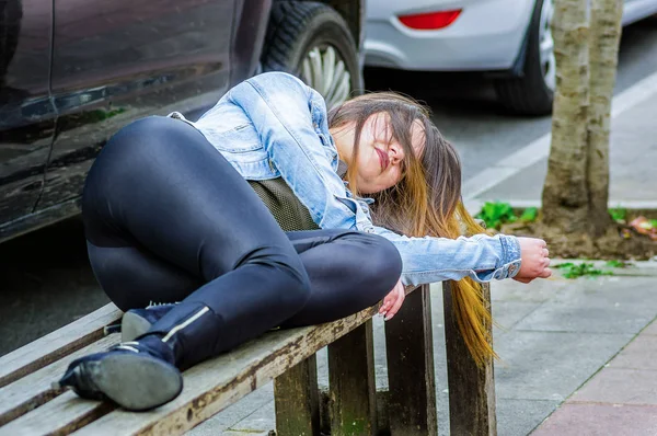 Hermosa joven bien vestida durmiendo en una silla pública en un parque, concepto adicto —  Fotos de Stock