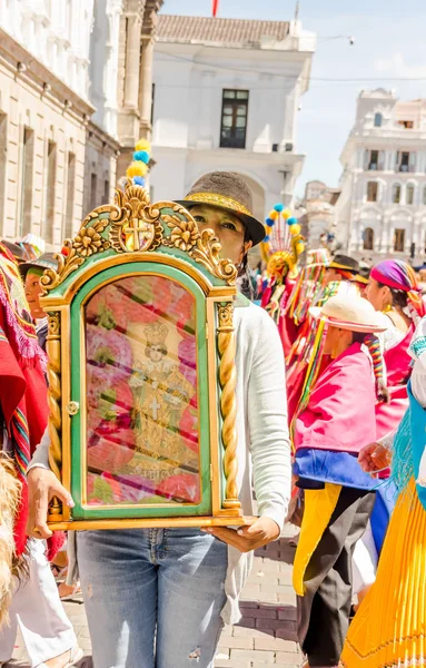 Quito, Ecuador - 11 januari 2018: Onbekende vrouw draagt een strooien hoed en houden een afbeelding binnenkant een gouden structuur en wandelen in de straten tijdens een parade in Quito, Ecuador — Stockfoto