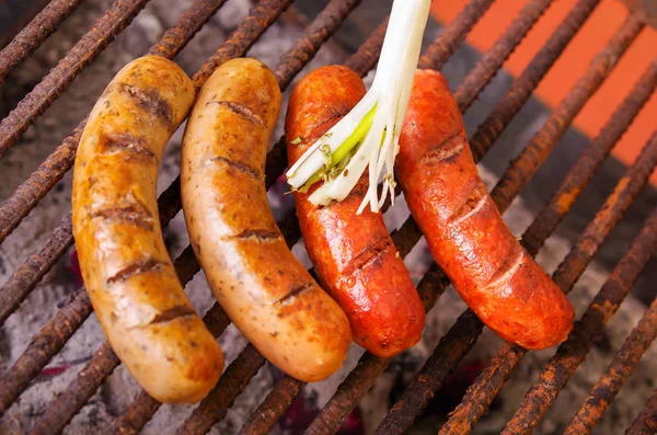 Close up of grilling sausages on barbecue grill with a long white onion. BBQ in the garden. Bavarian sausages — Stock Photo, Image