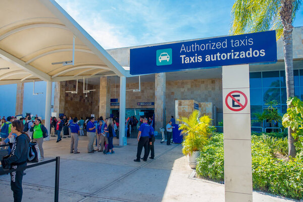 КАНКУН, МЕХИКО - 10 ЯНВАРЯ 2018 года: Информационный знак со многими неизвестными людьми, идущими и несущими свои багажи при въезде в международный аэропорт Канкун, Мексика
