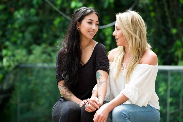 Dvojice hrdý lesbičky v venku při pohledu na sebe, zahradní pozadí — Stock fotografie
