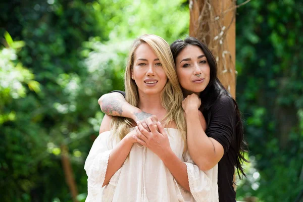 Un paio di orgogliose lesbiche all'aperto che si guardano l'un l'altra, in un giardino di sfondo — Foto Stock