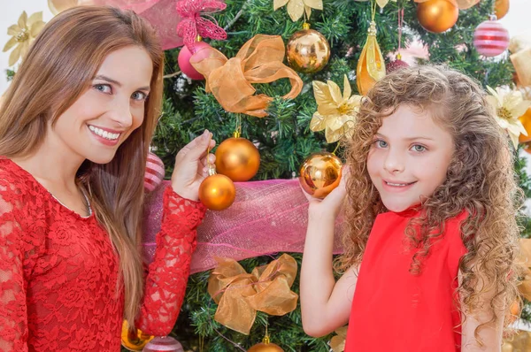 Close up van gelukkig meisje versieren kerstboom met haar moeder bedrijf gouden ballen, familie kerst concept — Stockfoto