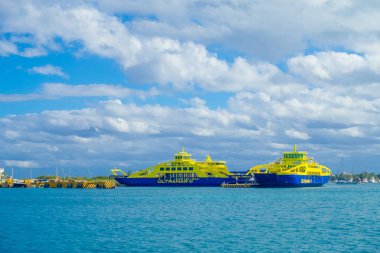 ISLA MUJERES, MEXICO, JANUARY 10, 2018: Outdoor view of ferry of color blue and yellow sailing in the waters close tothe Isla Mujeres . The island is some 7 kilometres long and 650 metres wide clipart