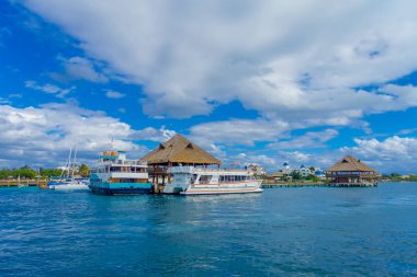 ISLA MUJERES, MEXICO, JANUARY 10, 2018: Outdoor view of ship in the shore with many passenger, close to a typical house from the Isla Mujeres . The island is some 7 kilometres long and 650 metres wide clipart