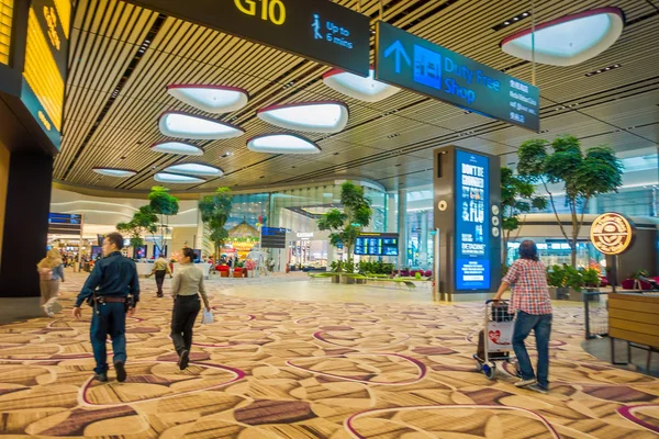 Singapore, singapore - 30. Januar 2018: Innenansicht von nicht identifizierten Leibwächtern, die in der Nähe eines Wartesaals mit einigen bunten Sofas im Inneren des internationalen Flughafens von Changi gehen — Stockfoto