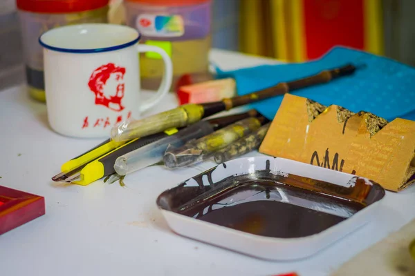 SINGAPORE, SINGAPORE - JANUARY 30, 2018: Close up of assorted tools with a brown painting inside of a plastic tray inside of a studio in Chinatown, Singapore — Stock Photo, Image