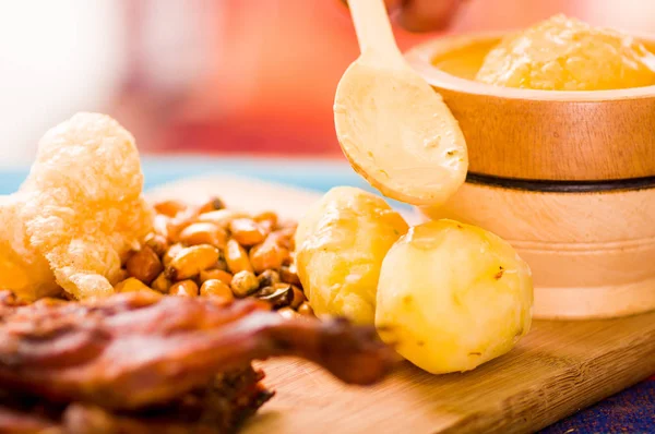 Corte pedaços de carne de porco guine cozido deitado na superfície de madeira ao lado de batatas, tostados e tigela de salsa — Fotografia de Stock