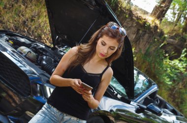 Sorunlu bir ROADTRIP, kenarda duran araba Siyah araba cep telefonunu kullanarak ve onun baş, siyah t-shirt ve kot pantolon, sunglases giyen güzel beyaz kadının yakın çekim