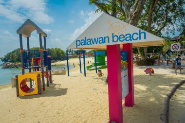 Singapore, Singapur - 01 Şubat 2018: plaj ve bilgilendirici işareti Sentosa Adası, Singapore, Beach Palawan pembe sütunlarla yürüyüş Tanımlanamayan kişi