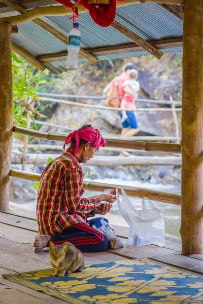 CHIANG RAI, TAILANDIA - 01 DE FEBRERO DE 2018: Vista al aire libre del hombre no identificado de rodillas con comida para peces en las manos dentro de un edificio en el Santuario de la Selva —  Fotos de Stock