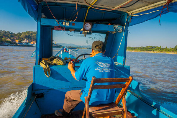 CHIANG RAI, THAILAND - FEBRUARY 01, 2018: Outdoor view of the captain in the cabin sailing a boat in the waters of port at golden triangle Laos
