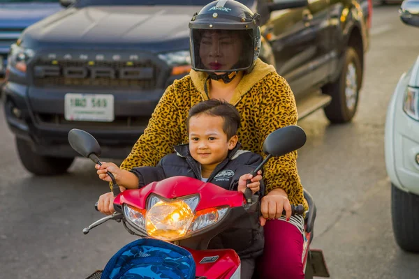 CHIANG RAI, TAILANDIA - 01 DE FEBRERO DE 2018: Mujer no identificada con su hijo usando una protección de casco y andar en moto es el transporte más popular en el sur de Asia, en Chiang Mai, Tailandia —  Fotos de Stock