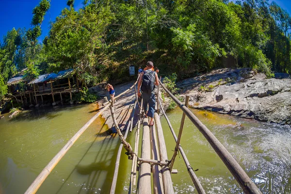 Chiang Rai, Thailand - februari 01, 2018: Outdoor weergave van niet-geïdentificeerde mensen lopen in het tropisch regenwoud met behulp van een houten brug over een riviertje in de provincie Chiang Mai, Thailand — Stockfoto