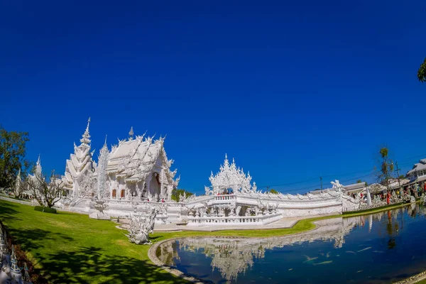 CHIANG RAI, THAILAND - FEBRUARY 01, 2018: Unidentified people taking pictures to white temple Wat Rong Khun located in Chiang Rai northern Thailand in sunny day with a natural pond — Stock Photo, Image