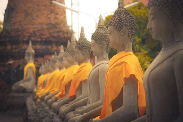 Nahaufnahme einer antiken Buddha-Statue in einer Reihe mit einem gelben Stoff am wat yai chai mongkol, der historischen Stadt Ayutthaya, Thailand — Stockfoto