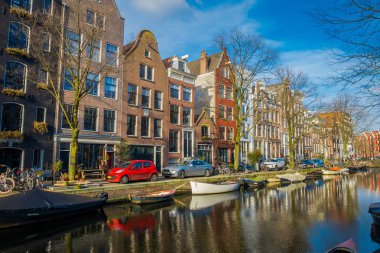 Amsterdam, Hollanda, Mart, 10 2018: Açık yakın bir teknelerle Amsterdam kanalları sokakta park edilmiş araba görünümüdür Hollanda'nın başkenti ve en kalabalık
