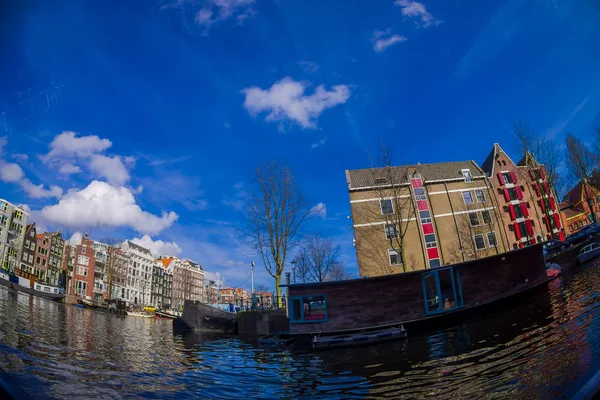 Άμστερνταμ, Ολλανδία, 10 Μαρτίου 2018: Πανέμορφη εξωτερική όψη του Πλωτά σπίτια και πολυκατοικίες πάνω σε ένα κανάλι στην πόλη του Άμστερνταμ — Φωτογραφία Αρχείου