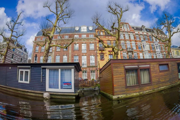 AMSTERDAM, NETHERLANDS, MARCH, 10 2018: Outdoor view of houseboats and apartment buildings behind on a canal in the city of Amsterdam — Stock Photo, Image