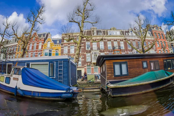AMSTERDAM, NETHERLANDS, MARCH, 10 2018: Outdoor view of houseboats and apartment buildings behind on a canal in the city of Amsterdam — Stock Photo, Image