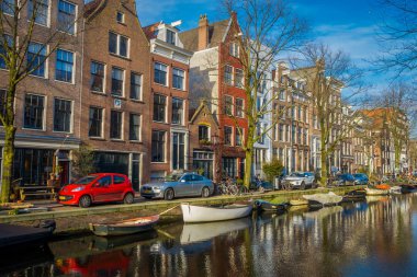 Amsterdam, Hollanda, Mart, 10 2018: Açık yakın bir teknelerle Amsterdam kanalları sokakta park edilmiş araba görünümüdür Hollanda'nın başkenti ve en kalabalık
