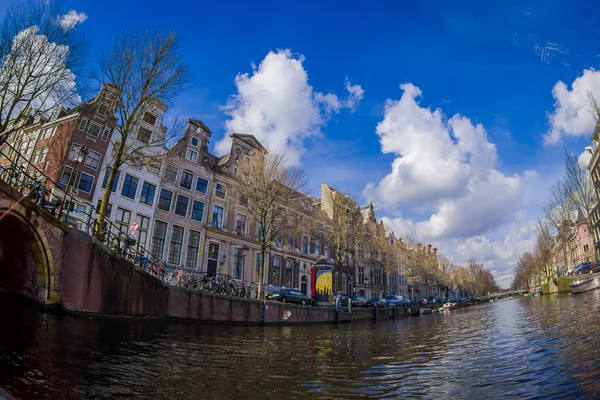 АМСТЕРДАМ, НИДЕРЛАНДЫ, МАРТ, 10 МАРТА 2018: Открытый вид на амстердамские каналы с мостом и типичными дачными домиками. Голландия — стоковое фото