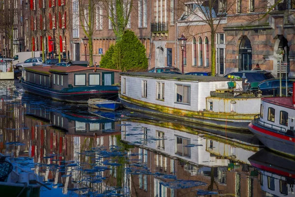 Άμστερνταμ, Ολλανδία, 10 Μαρτίου 2018: Όμορφη θέα των σπιτιών και βάρκες στο κανάλι στο Άμστερνταμ, σε ολλανδικό στιλ με αντανάκλαση στο νερό — Φωτογραφία Αρχείου