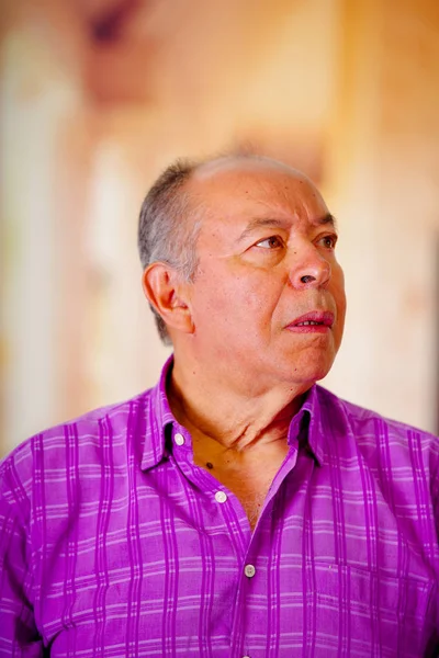 Портрет удивленного взрослого мужчины с открытым ртом и в фиолетовой квадратной футболке на размытом фоне — стоковое фото