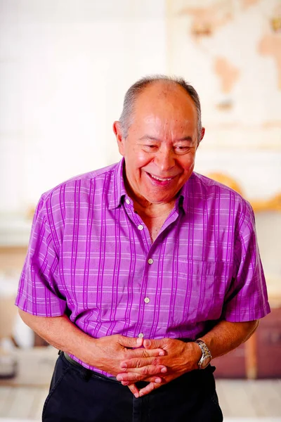 Портрет счастливого зрелого мужчины, смеющегося очень громко, который не может остановиться и дотронуться до живота обеими руками и носить фиолетовую квадратную футболку на размытом фоне — стоковое фото
