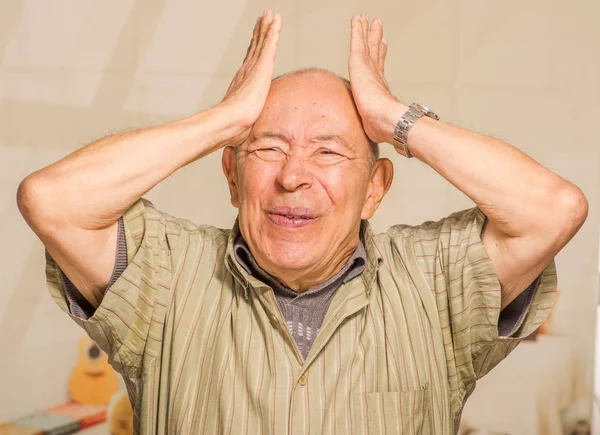 Портрет беспокойного взрослого мужчины, держащего голову обеими руками на размытом фоне — стоковое фото