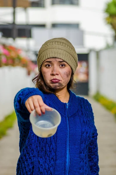 Vista al aire libre de la mujer triste sin hogar en la calle en el frío clima de otoño sosteniendo un matraz de plástico vacío en sus manos pidiendo dinero, en la acera — Foto de Stock