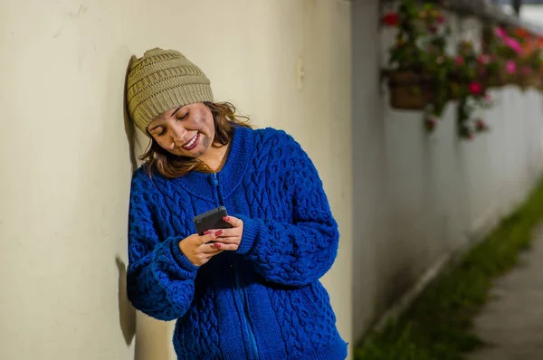 Vista al aire libre de la mujer sin hogar en la calle en el frío clima otoñalusando un teléfono celular en la acera —  Fotos de Stock