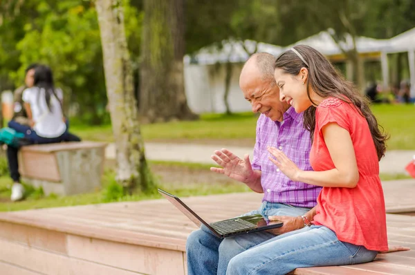 Far och dotter med en dator i parken — Stockfoto