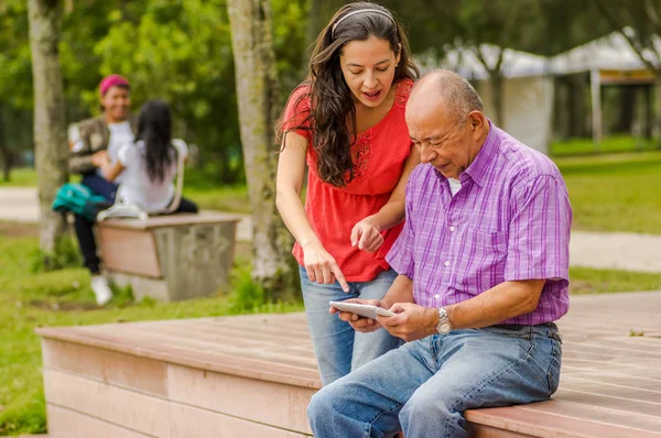 Vista al aire libre del padre y la hija usando un teléfono celular en el parque — Foto de Stock