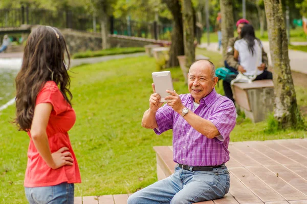 Vista al aire libre del padre tomando fotos con una tableta a su hija en el parque — Foto de Stock