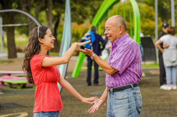 Vista ao ar livre da filha e do pai brincando com as mãos ao ar livre no parque — Fotografia de Stock
