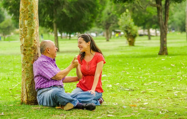 Vista ao ar livre de pai e filha com tocos para cima ao ar livre sentado no chão, no parque — Fotografia de Stock