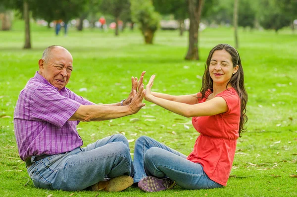 Vista ao ar livre de pai e filha rejeitando uns aos outros ao ar livre sentado na grama, no parque — Fotografia de Stock