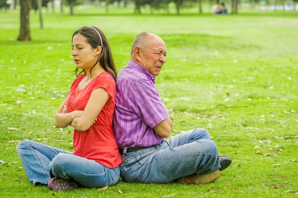 Venkovní pohled na otce a dceru sedí v trávě a zády k sobě na venku, v parku — Stock fotografie