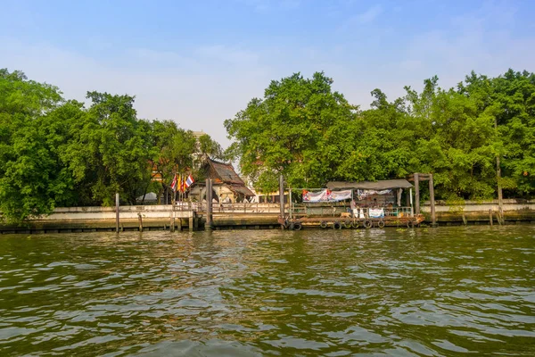 Bangkok, Thailand, mars 23, 2018: Utomhus utsikt över byggnader och gröna skogen framme vid flodstranden på floden Chao Phraya. Thailand — Stockfoto