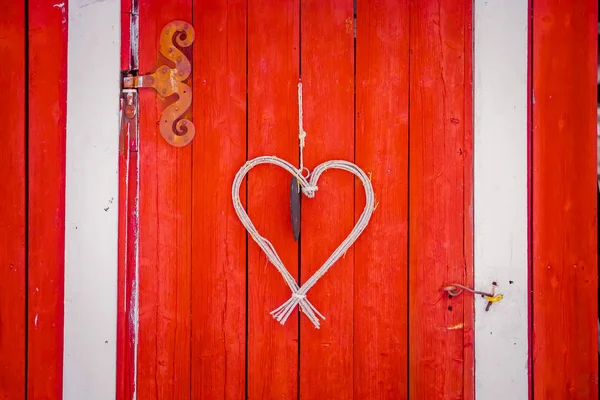 Close up of heart made of branches hanging in from a red door in a winter season in Norway — Stock Photo, Image