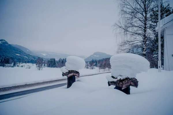 Vista de neve de estrada de inverno e gelo com algumas caixas de madeira, cobertas com neve em um lado da estrada na Noruega — Fotografia de Stock