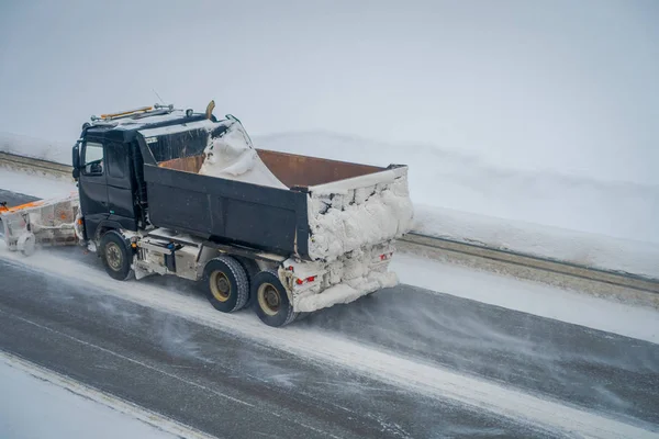 Valdres, Norway - March 26, 2018: Above view of snow-removing machine cleans the street of the road from the snow in the morning snow-covered trees and roads in Norway — Stock Photo, Image